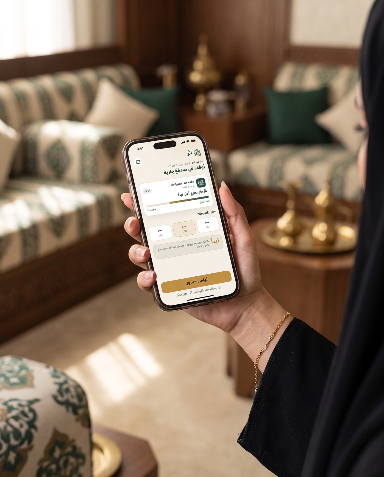 واقفة تمسك جوالاً يعرض تطبيق أثَر